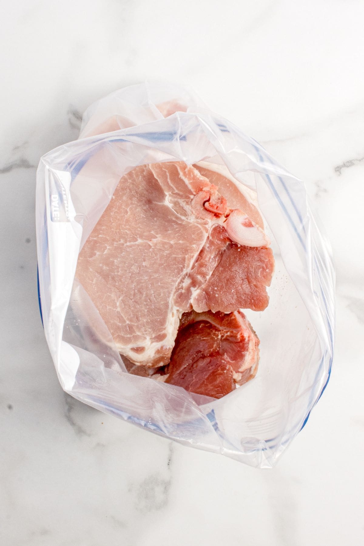 Pork chops placed in a zip top plastic bag.