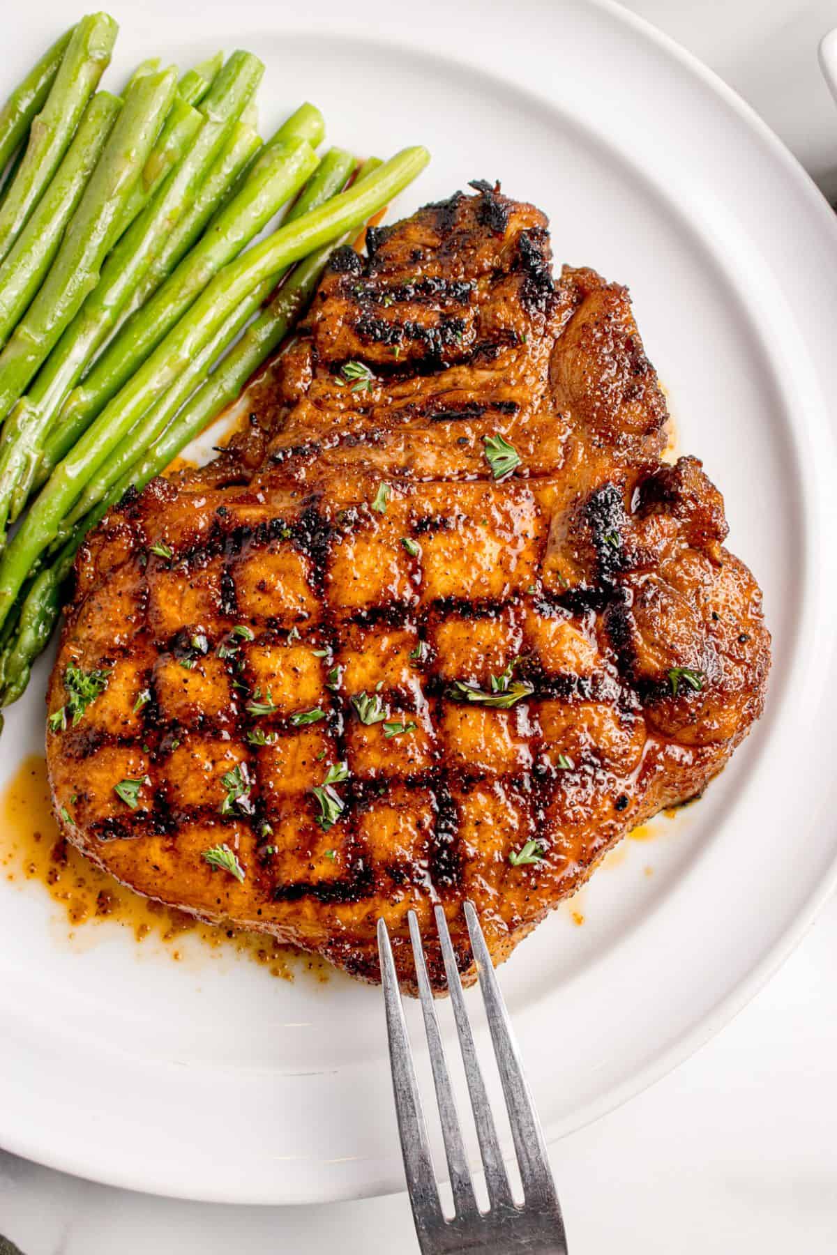 Completed pork chop on a white dinner plate.