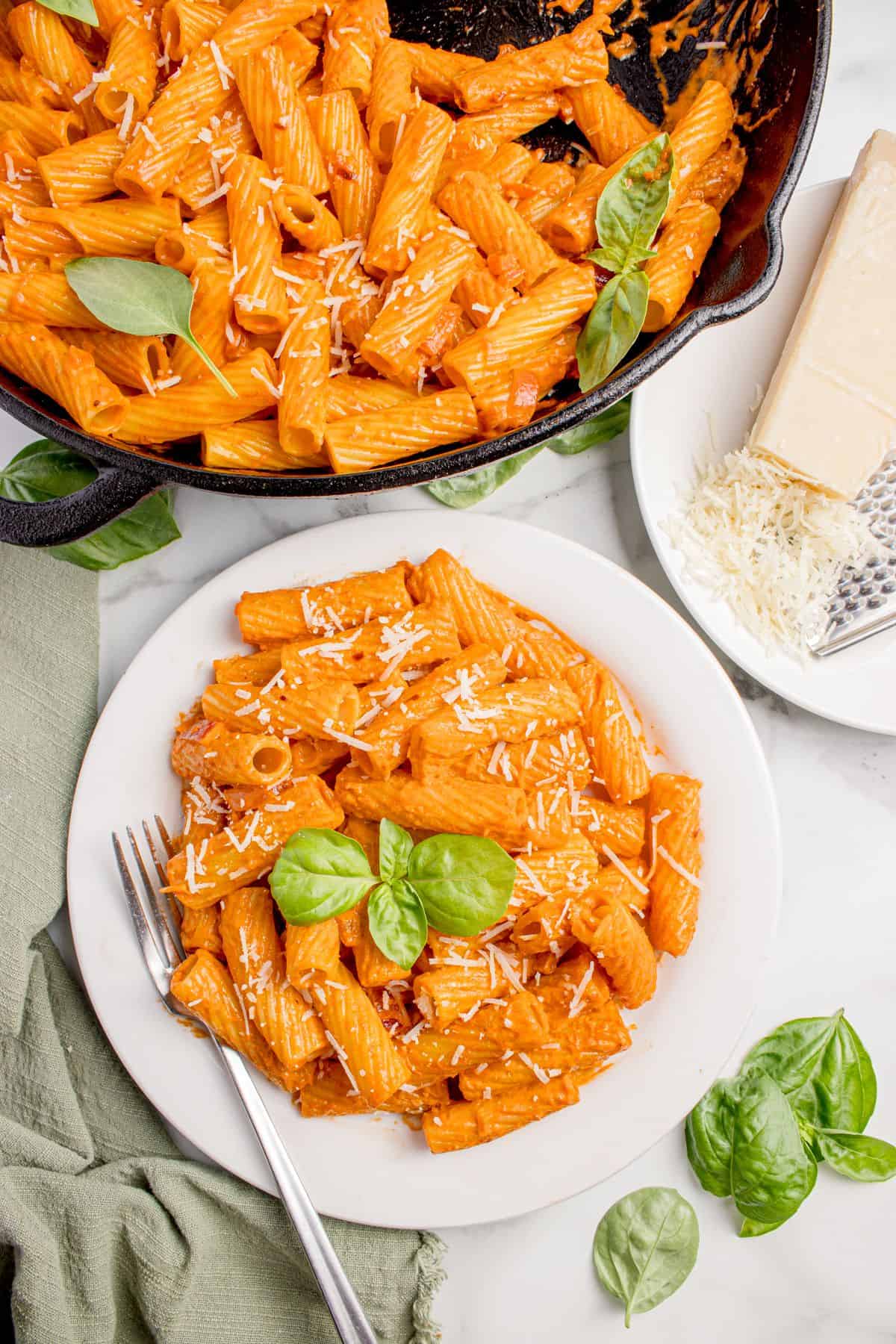 Completed spicy rigatoni on a white dinner plate. The cast iron pan of pasta is just above the dinner plate.