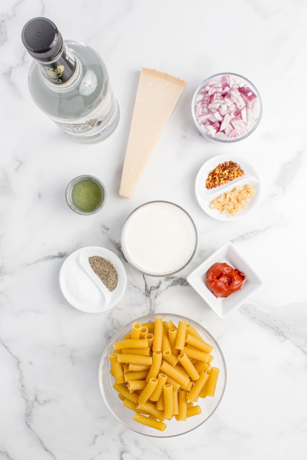 Ingredients for spicy rigatoni: rigatoni pasta, olive oil, red onion, garlic, red pepper flakes, tomato paste, vodka, heavy cream, parmesan cheese, salt, and black pepper.