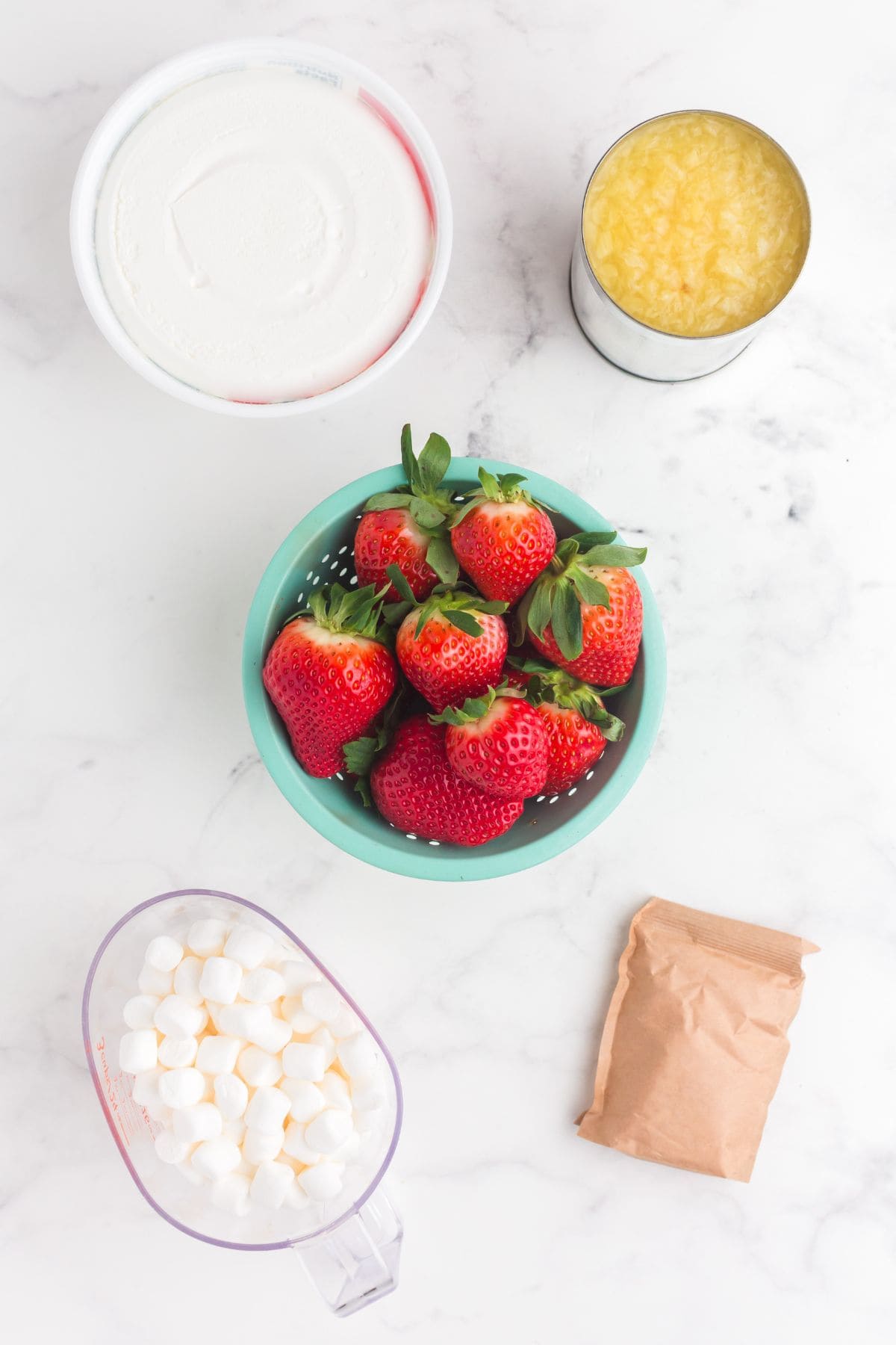 Ingredients for strawberry fluff: Canned pineapple, fresh strawberries, strawberry Jello, mini marshmallows, and Cool Whip.