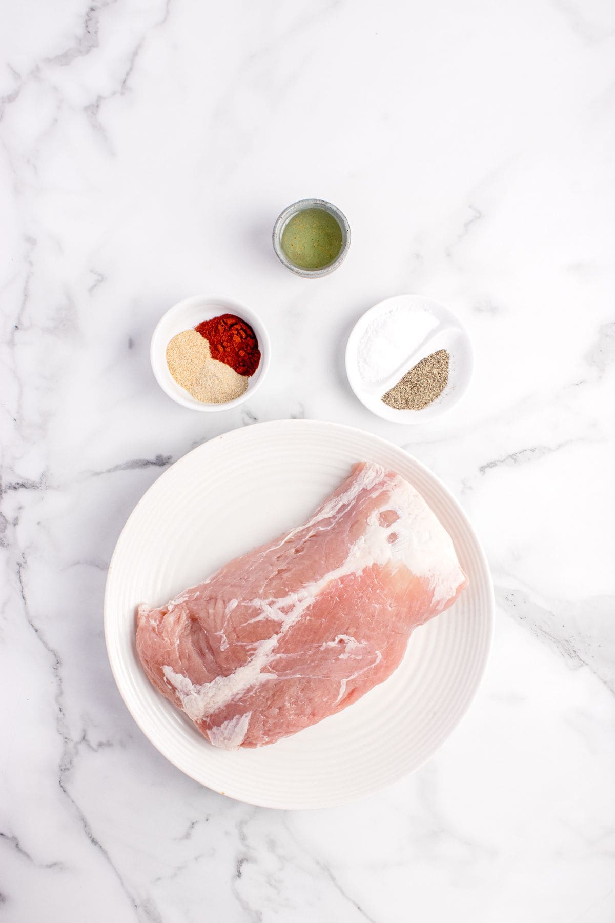 Ingredients for grilled pork loin: pork loin, salt, garlic powder, onion powder, paprika, black pepper, and olive oil.