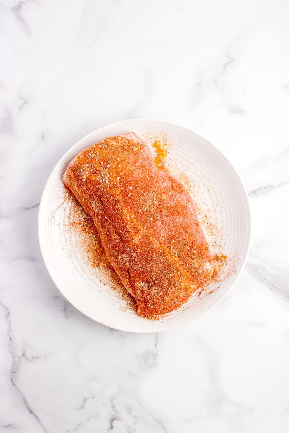 Pork loin seasoned on a white plate.