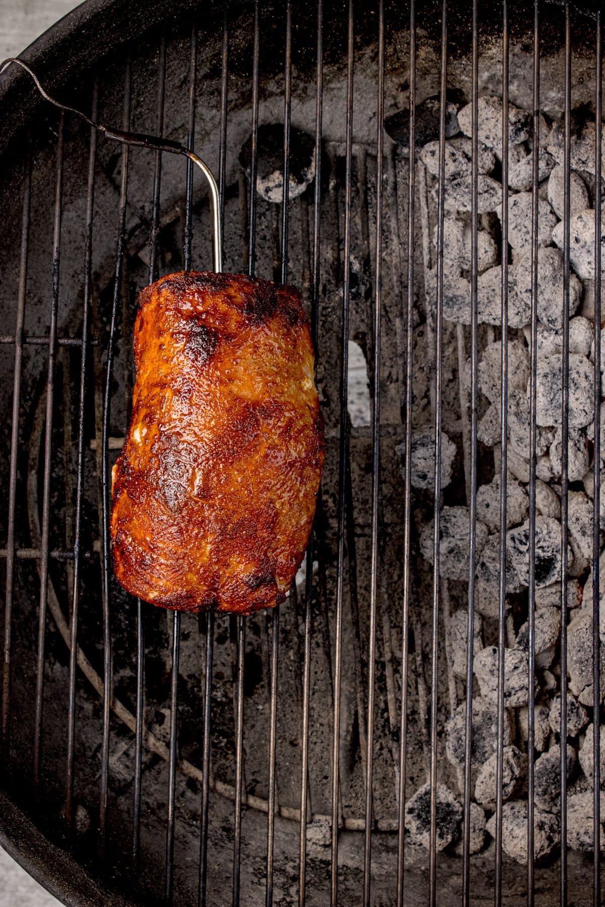 Pork loin cooking on a charcoal grill.