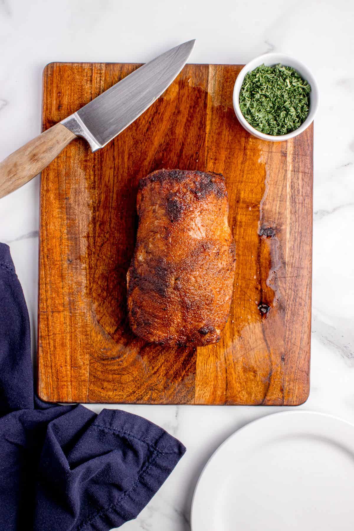 Pork loin resting on a wooden cutting board.