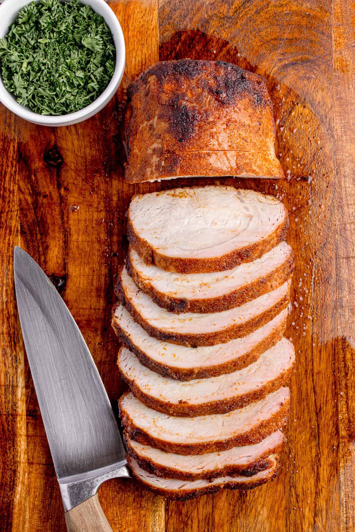 Grilled pork loin sliced on a wooden cutting board.