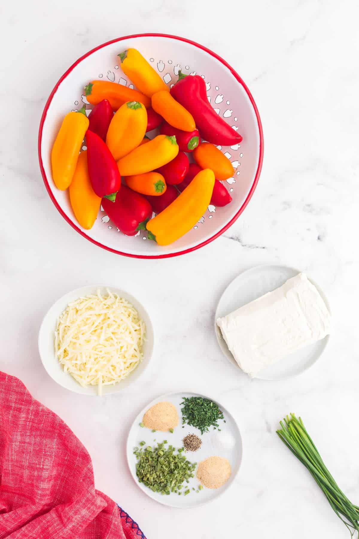 Ingredients for cream cheese stuffed peppers: mini peppers, cream cheese, shredded blended cheese, parmesan and roma, dried chives, parsley, garlic powder, onion powder, salt, and pepper.