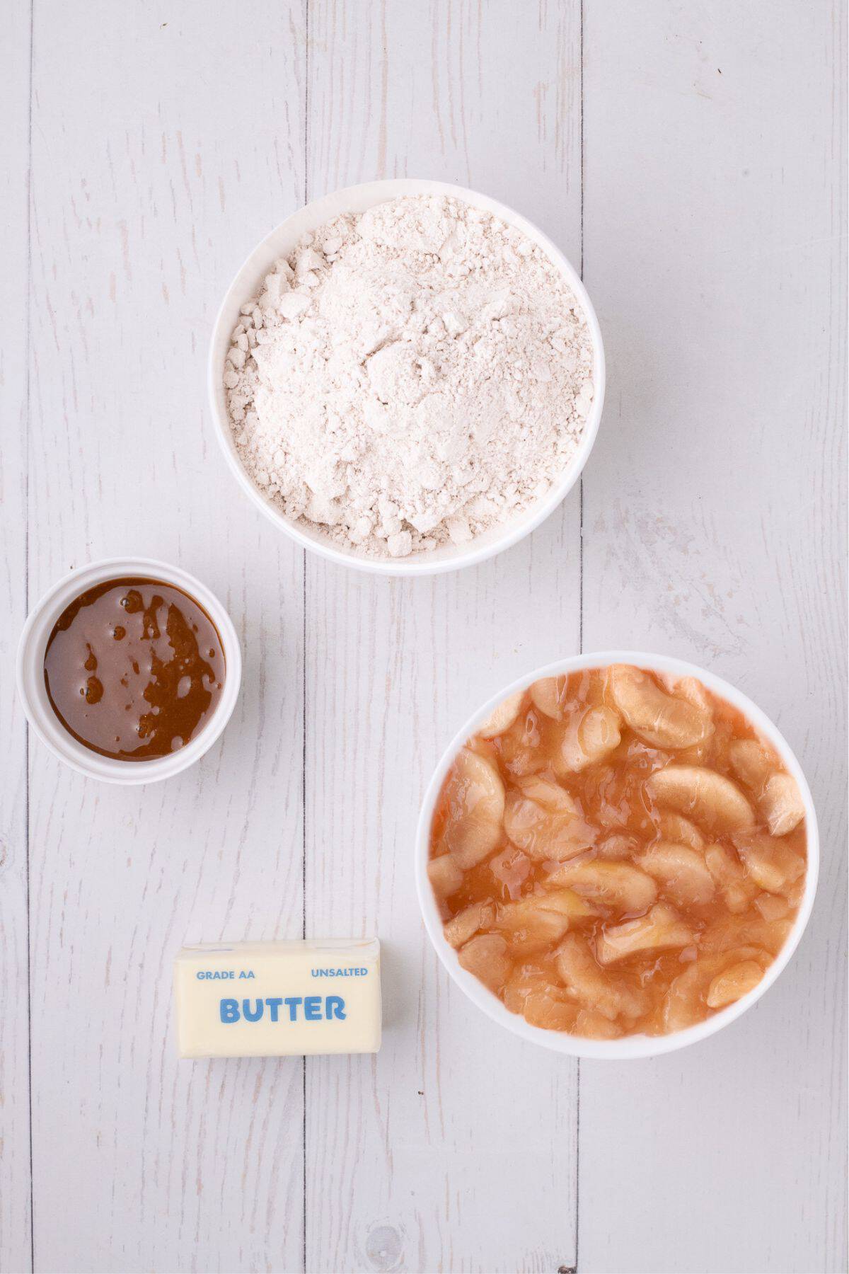 Ingredients for apple dump cake: box of spiced cake mix, store bought caramel sauce, apple pie filling, and butter.