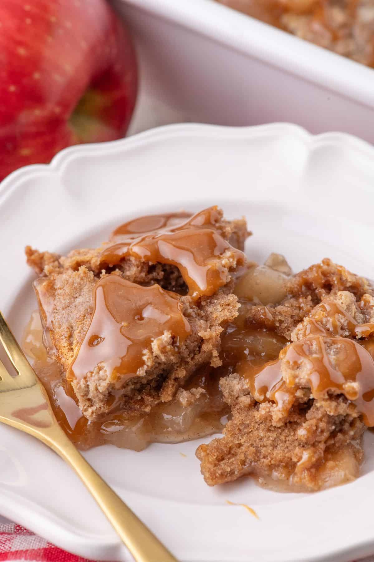 Apple dump cake on a white plate with a gold fork.