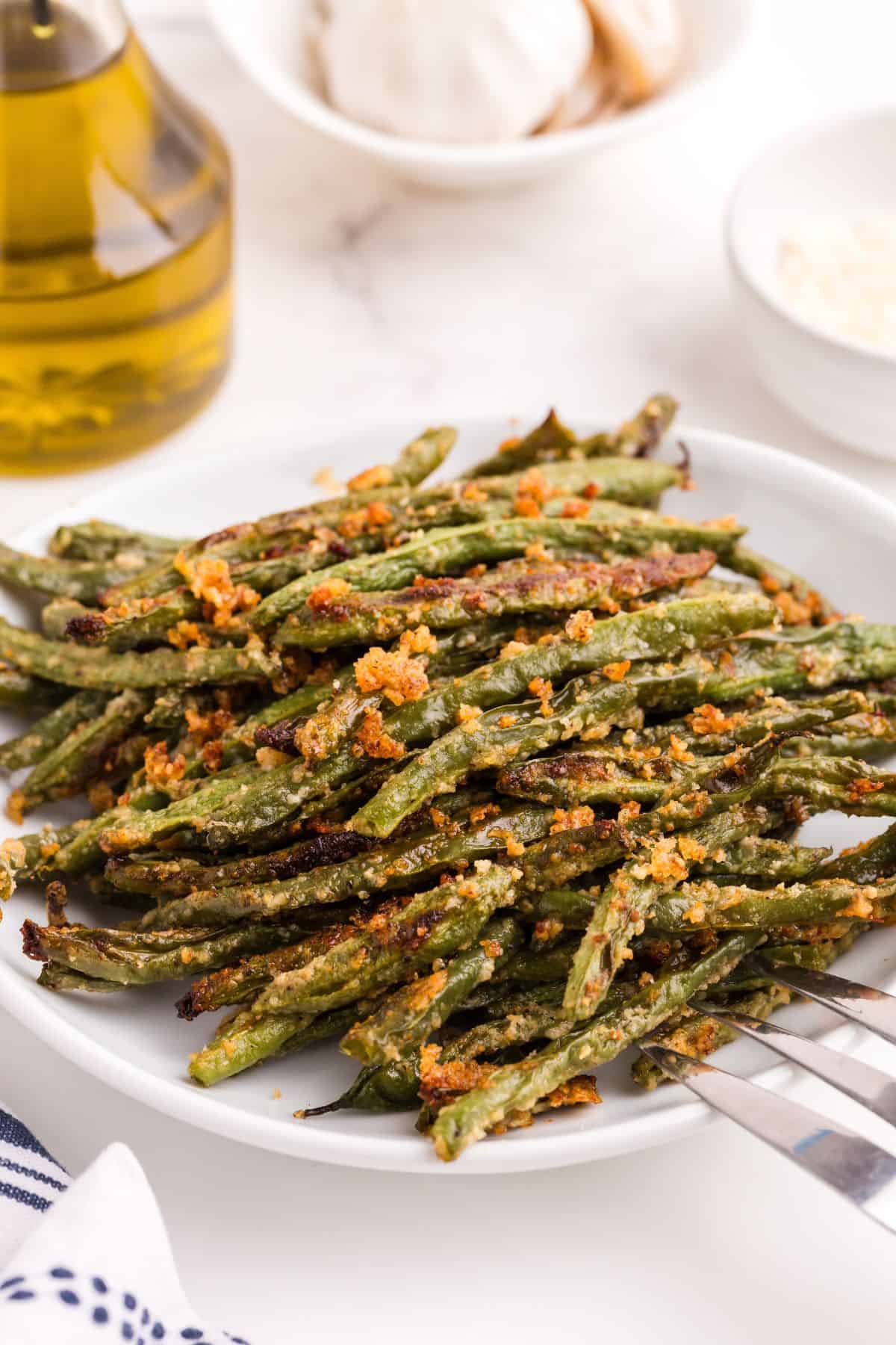 Baked green beans on a serving plate with a large serving fork.