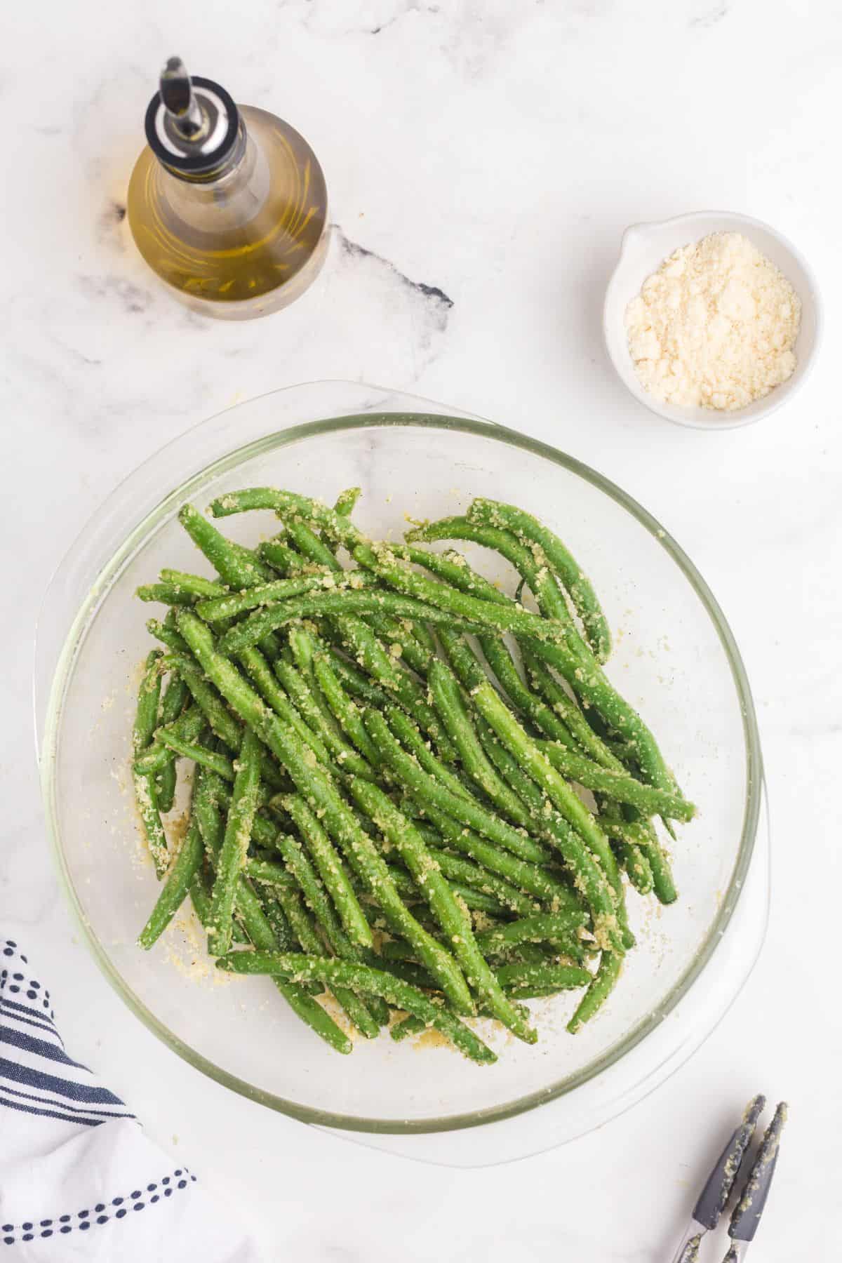 Unbaked, seasoned green beans in a glass mixing bowl.