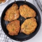 Parm crusted pork chops in an oven safe pan cooked and golden brown.