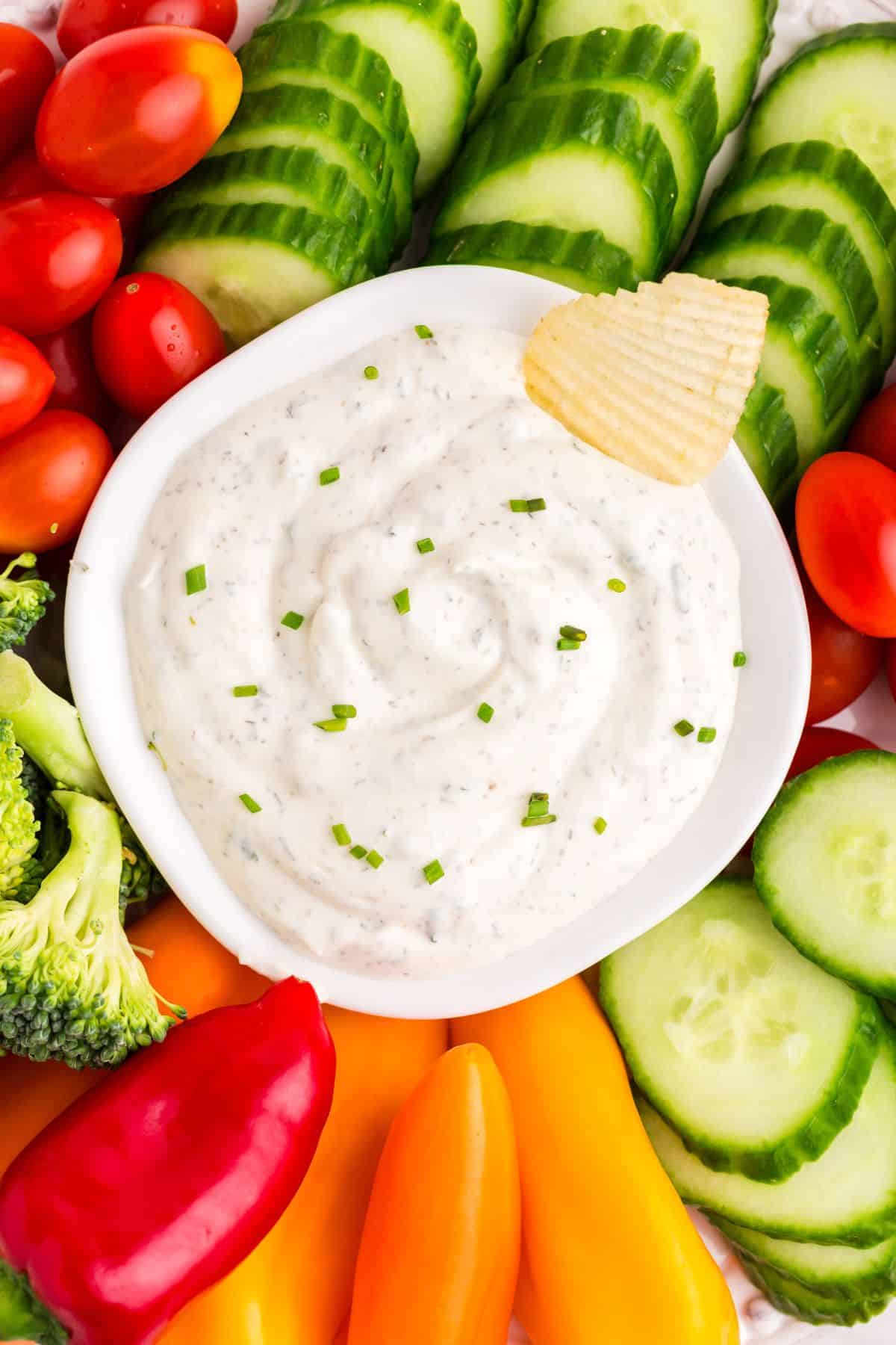 Overhead view of the ranch dip surrounded with veggies and a chip inside the dip in the middle.