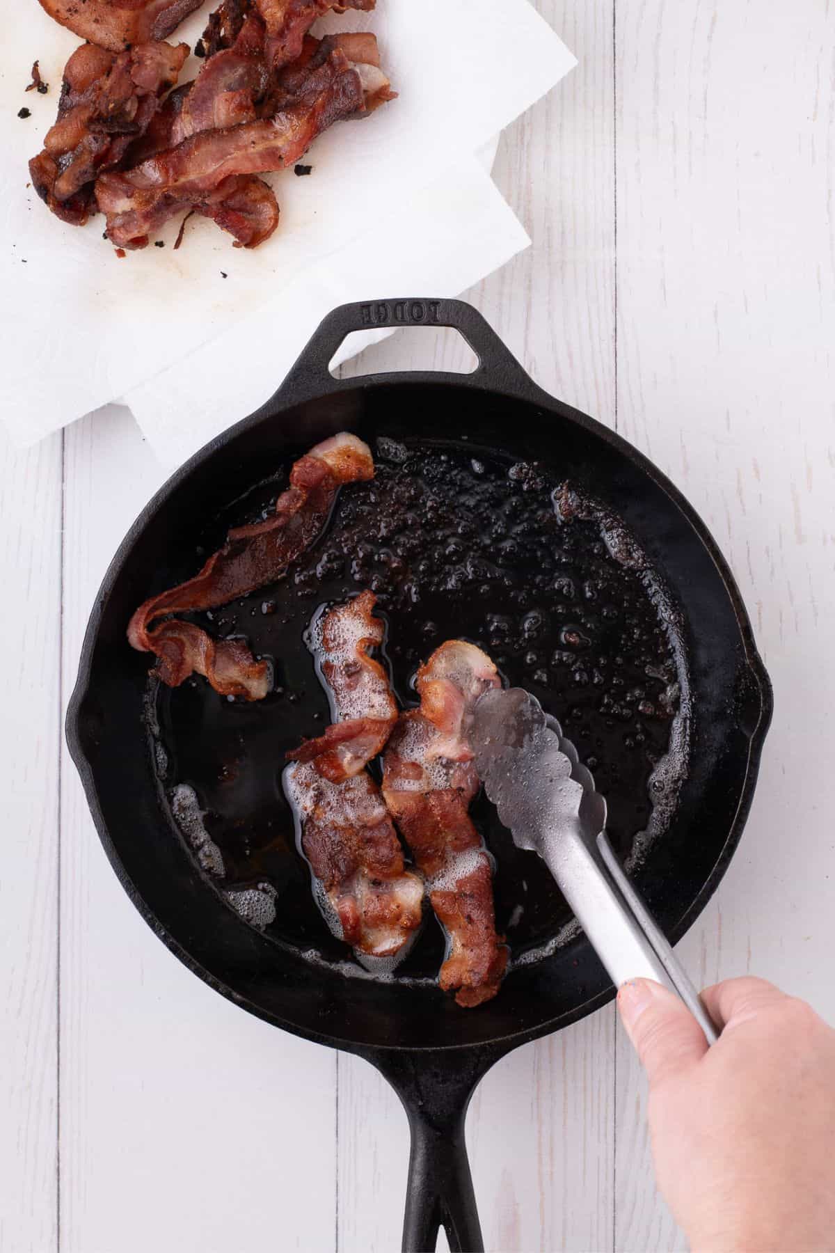 Bacon cooking in a cast iron pan.
