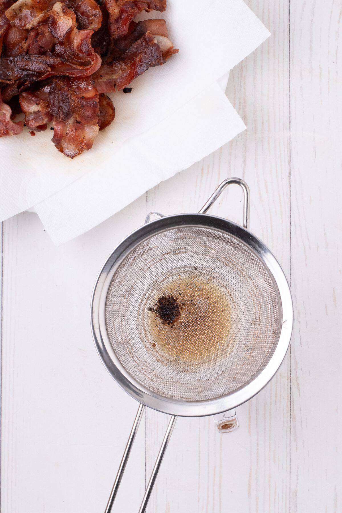 Bacon grease is strained with a fine mesh strainer to get the small burnt bits out.