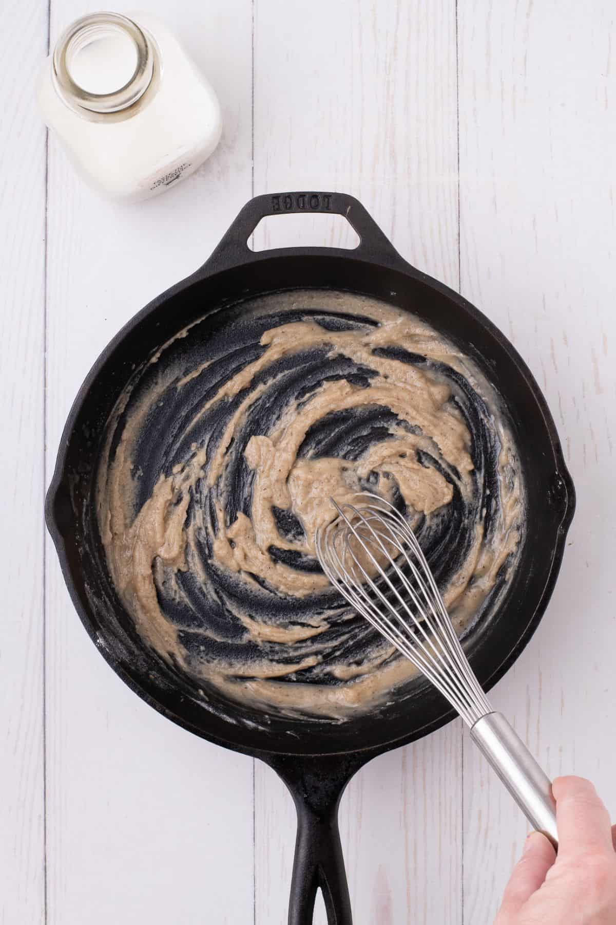 Bacon grease and flour are whisked together in a cast iron skillet.