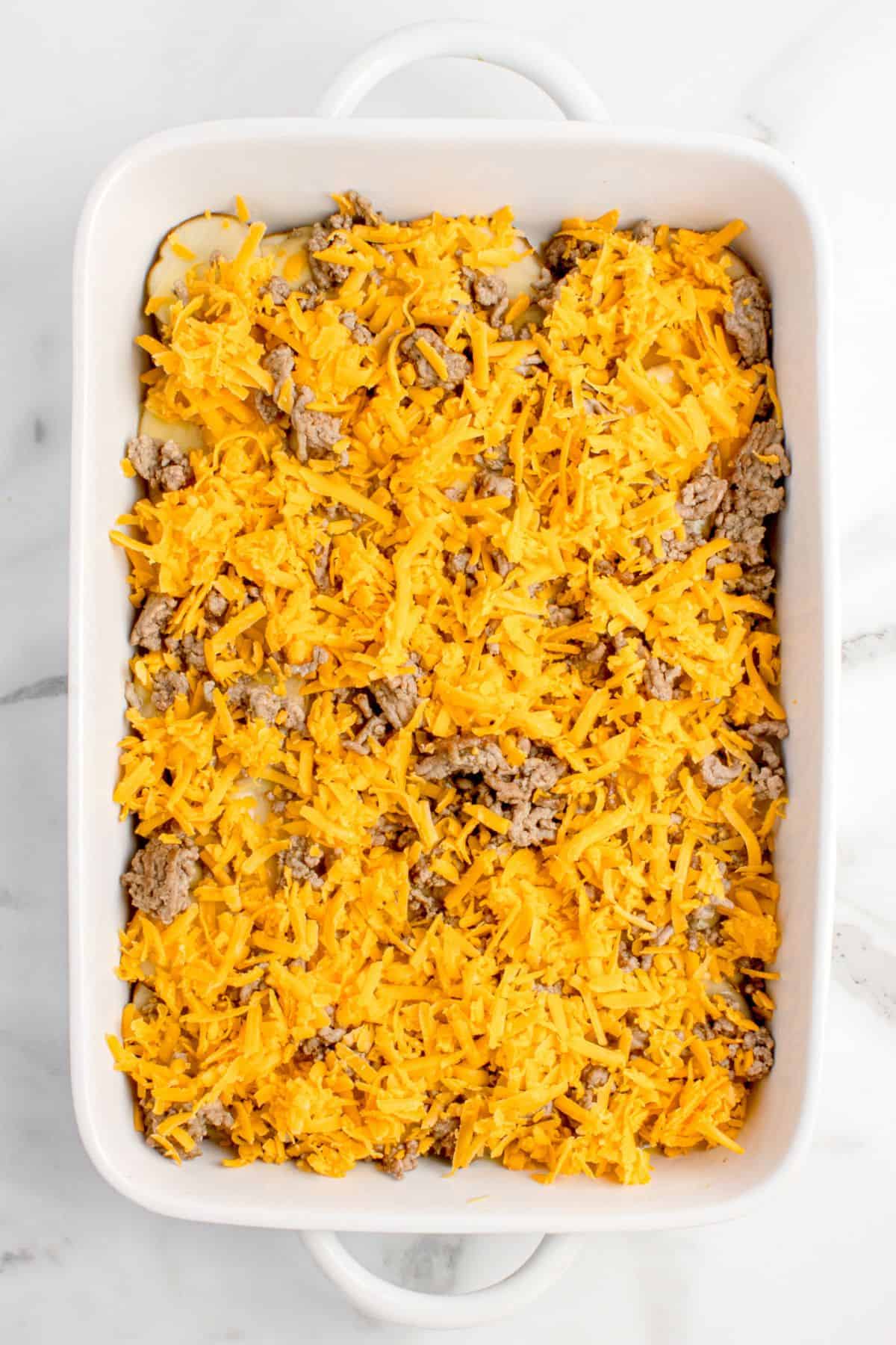 Add shredded cheese to the ground beef layer.