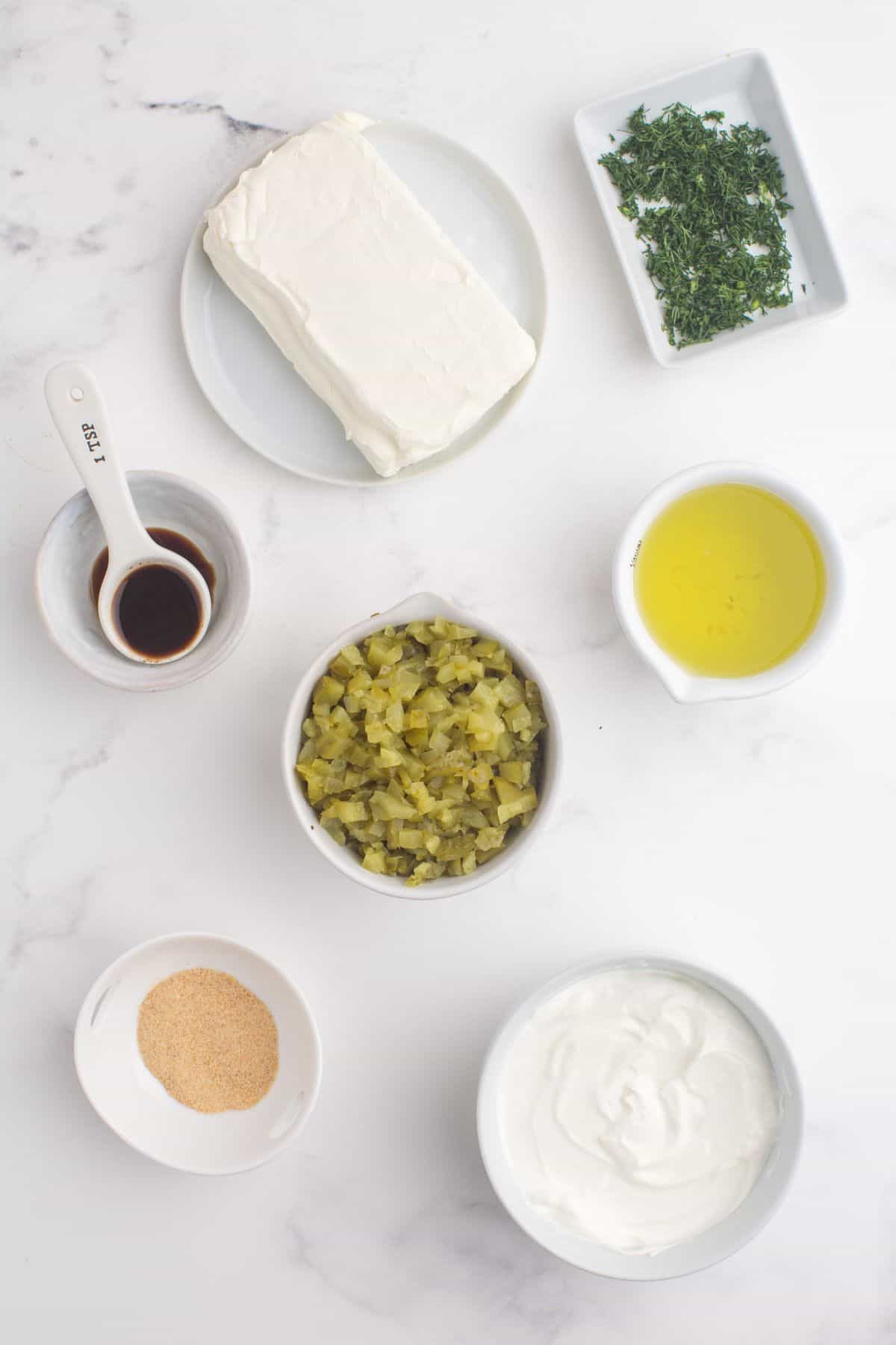 Ingredients for dill pickle dip: Fresh dill, cream cheese, worcestershire sauce, dill pickles, dill pickle juice, garlic powder, and sour cream.