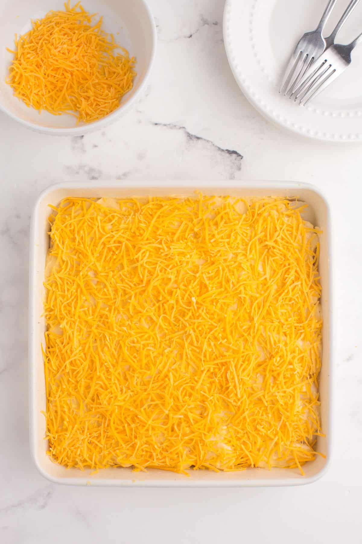 Assembled scalloped potatoes layered in a baking dish.