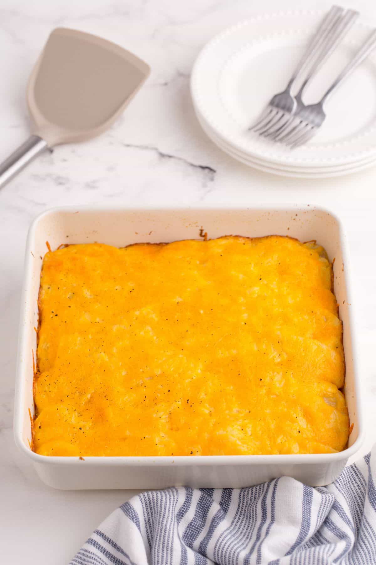Completed scalloped potatoes in a white baking dish.