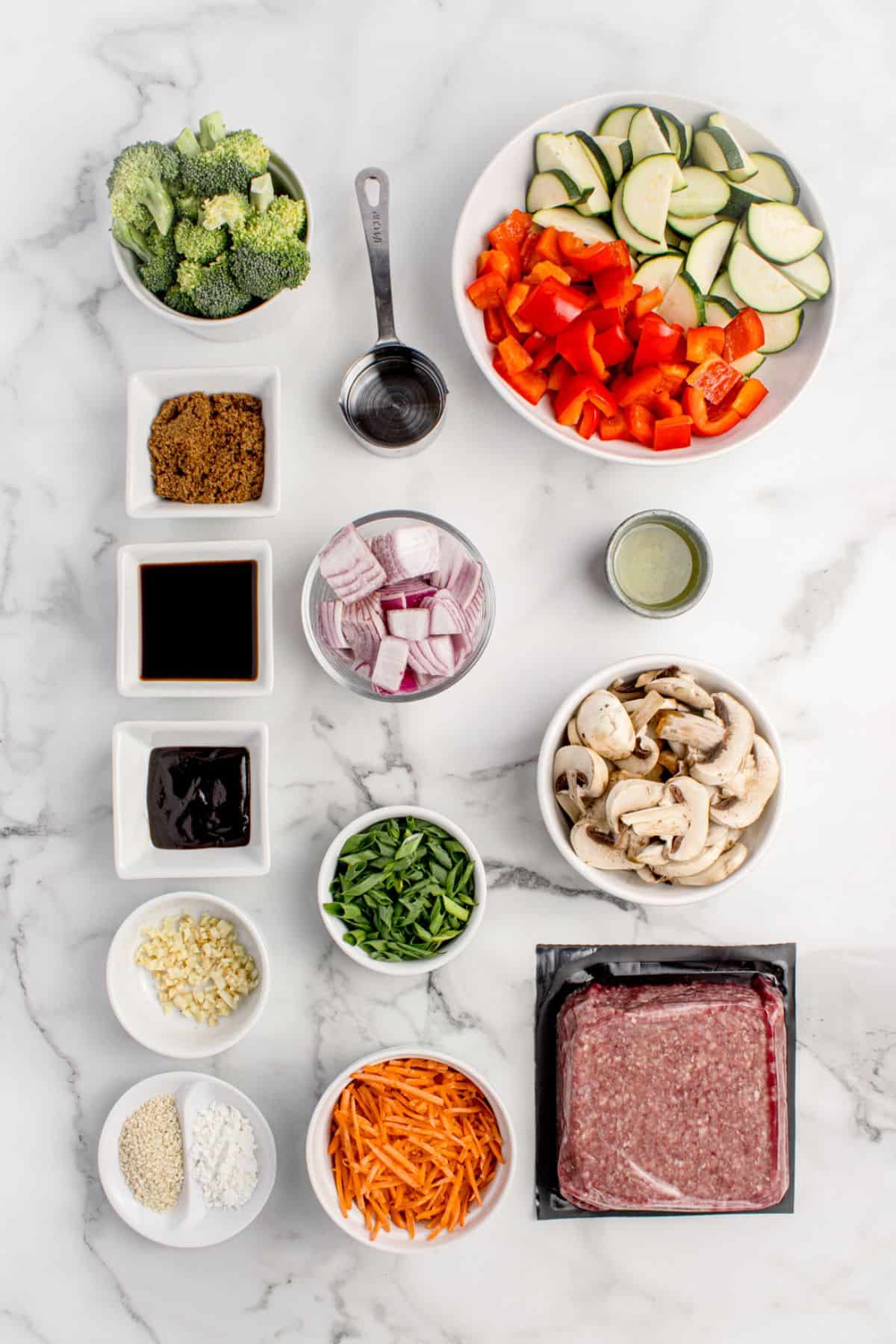 Ingredients for ground beef stir fry: ground beef, cooking oil, red bell pepper, red onion, broccoli, zucchini, cloves, mushrooms, carrots, soy sauce, brown sugar, hoisin sauce, water, and cornstarch.