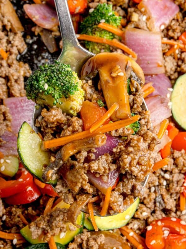 Stir fry on a serving spoon lifted above the cast iron pan.