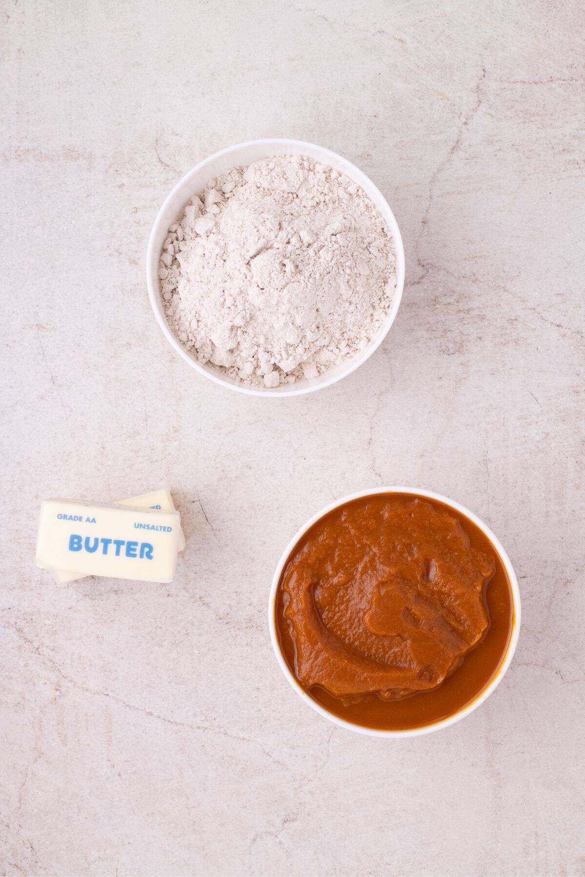 Ingredients for pumpkin dump cake: pumpkin pie filling, butter, and spice cake mix.