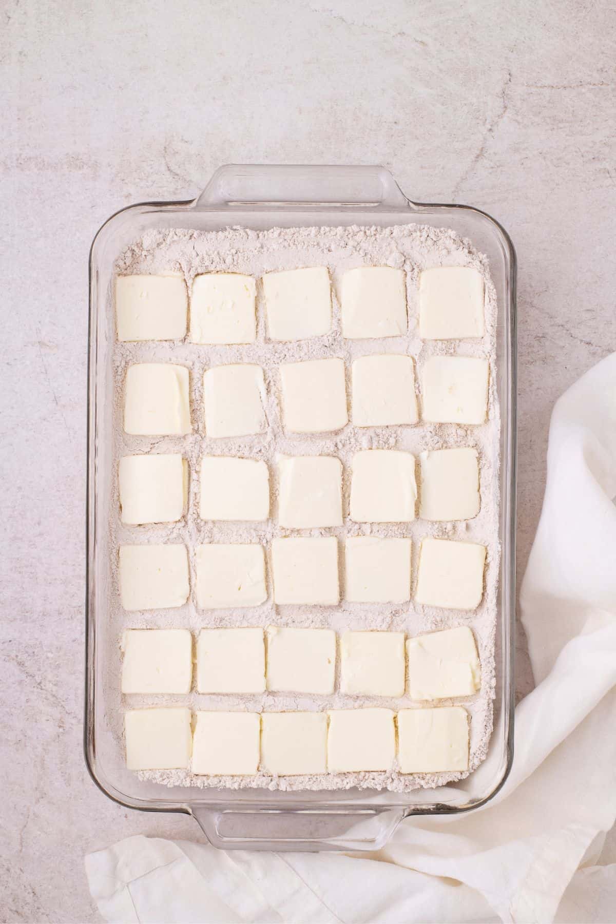 Pats of butter are spread out over the top of the baking pan.