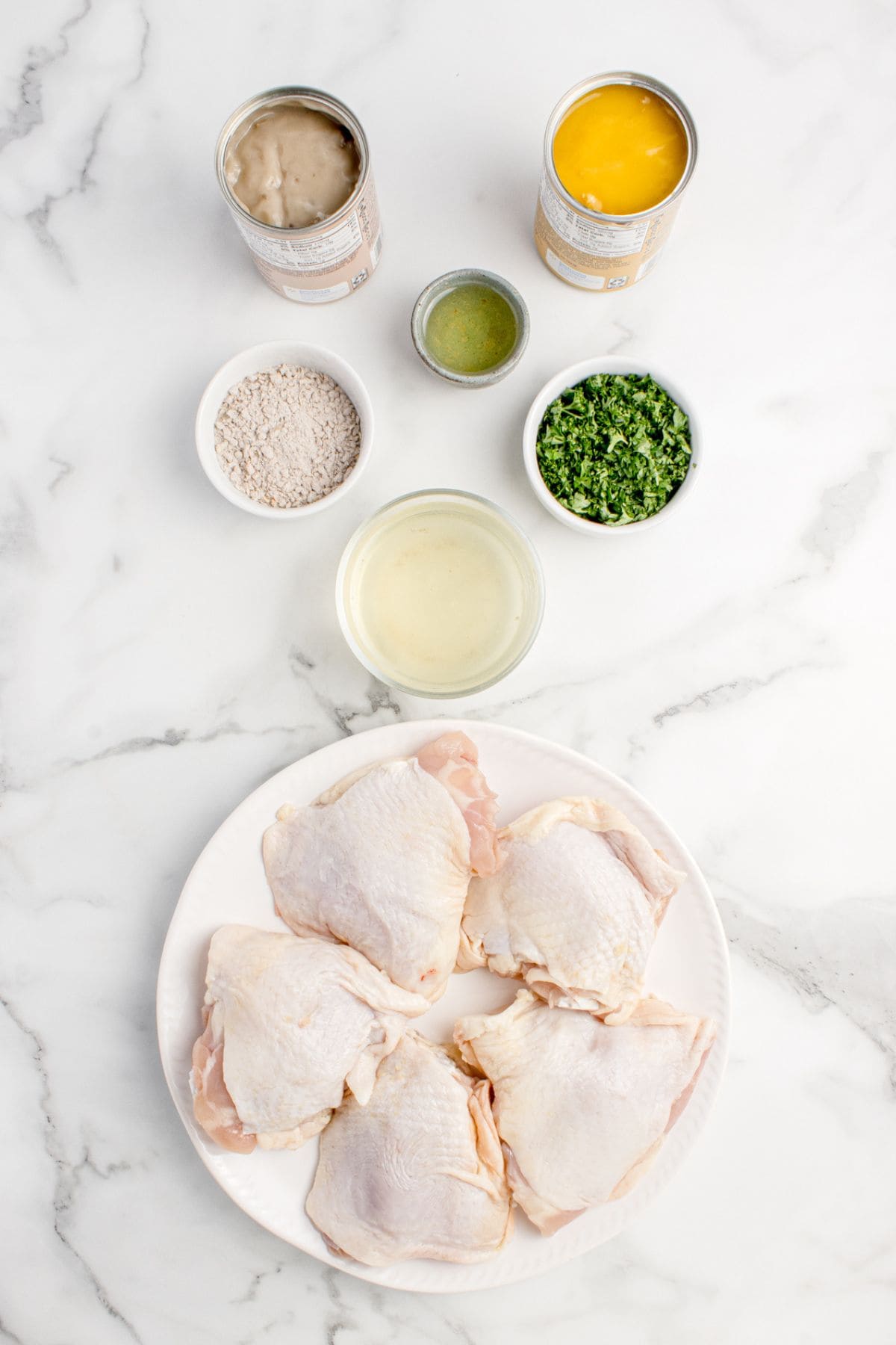 Ingredients for smothered chicken thighs: chicken thighs, onion soup mix, vegetable oil, cream of mushroom soup, cream of chicken soup, chicken broth, and parsley.