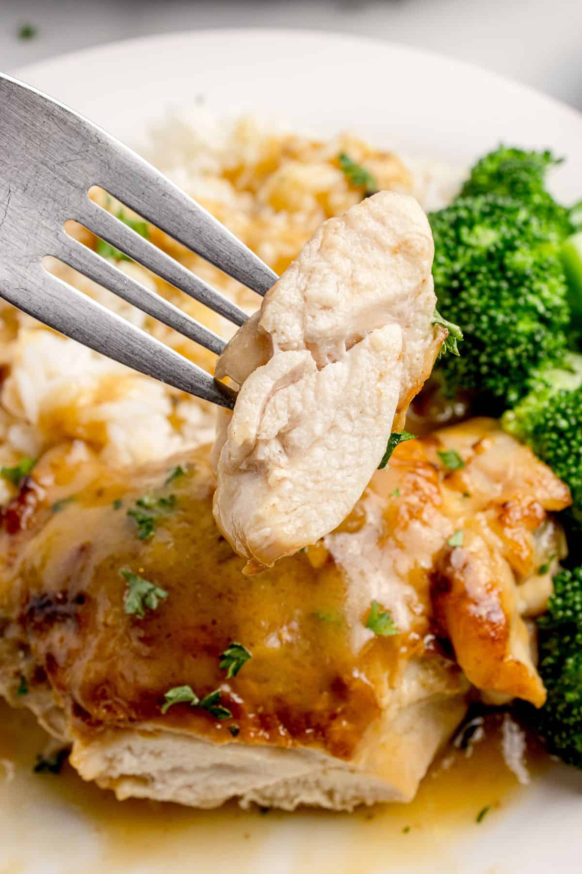 A slice of chicken is lifted up on a fork to show the interior.