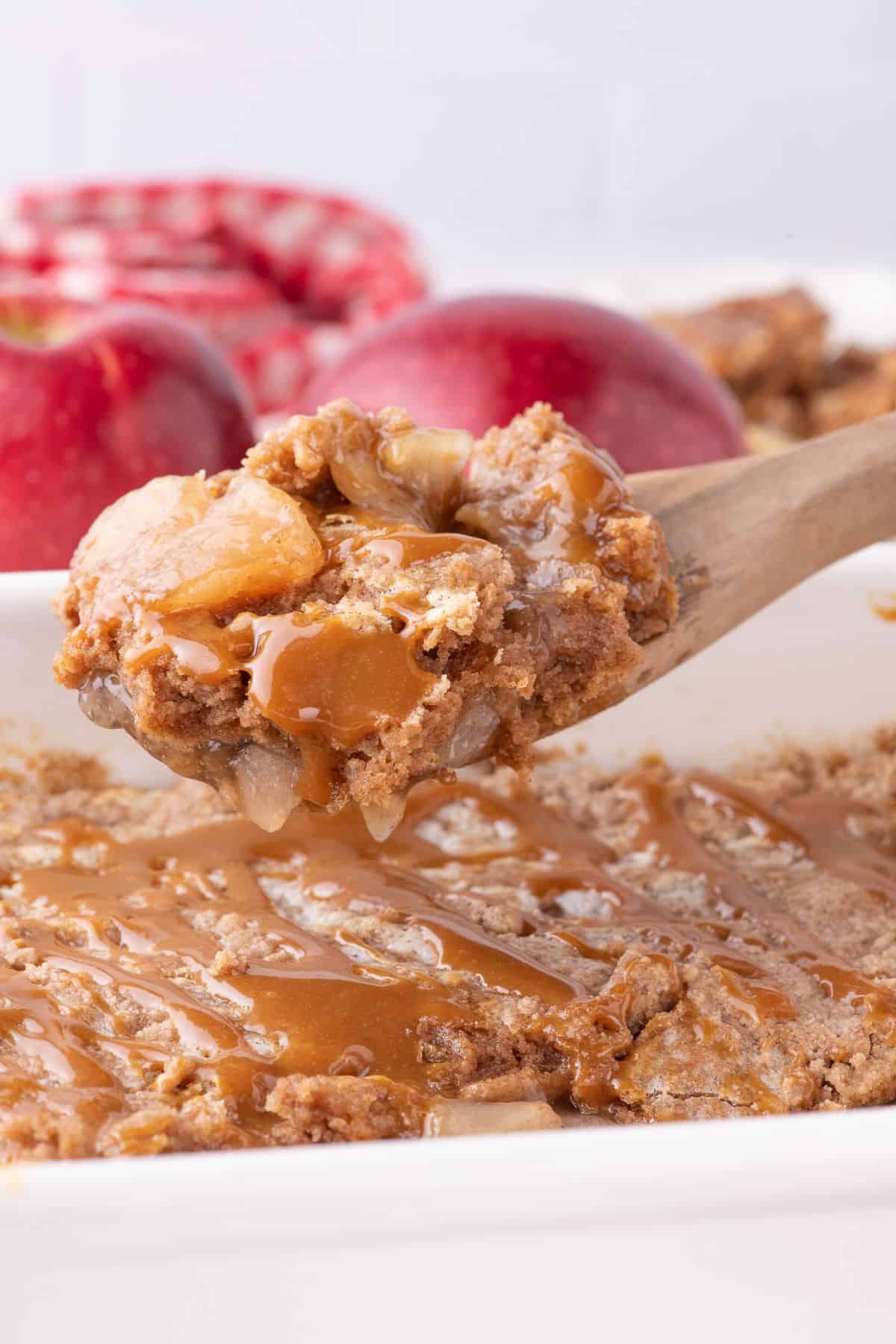 Apple dump cake being picked up with a wooden spoon.