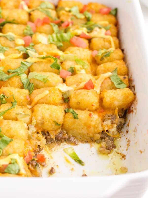 A white baking dish with big mac casserole. A portion has been removed from the corner of the baking dish.