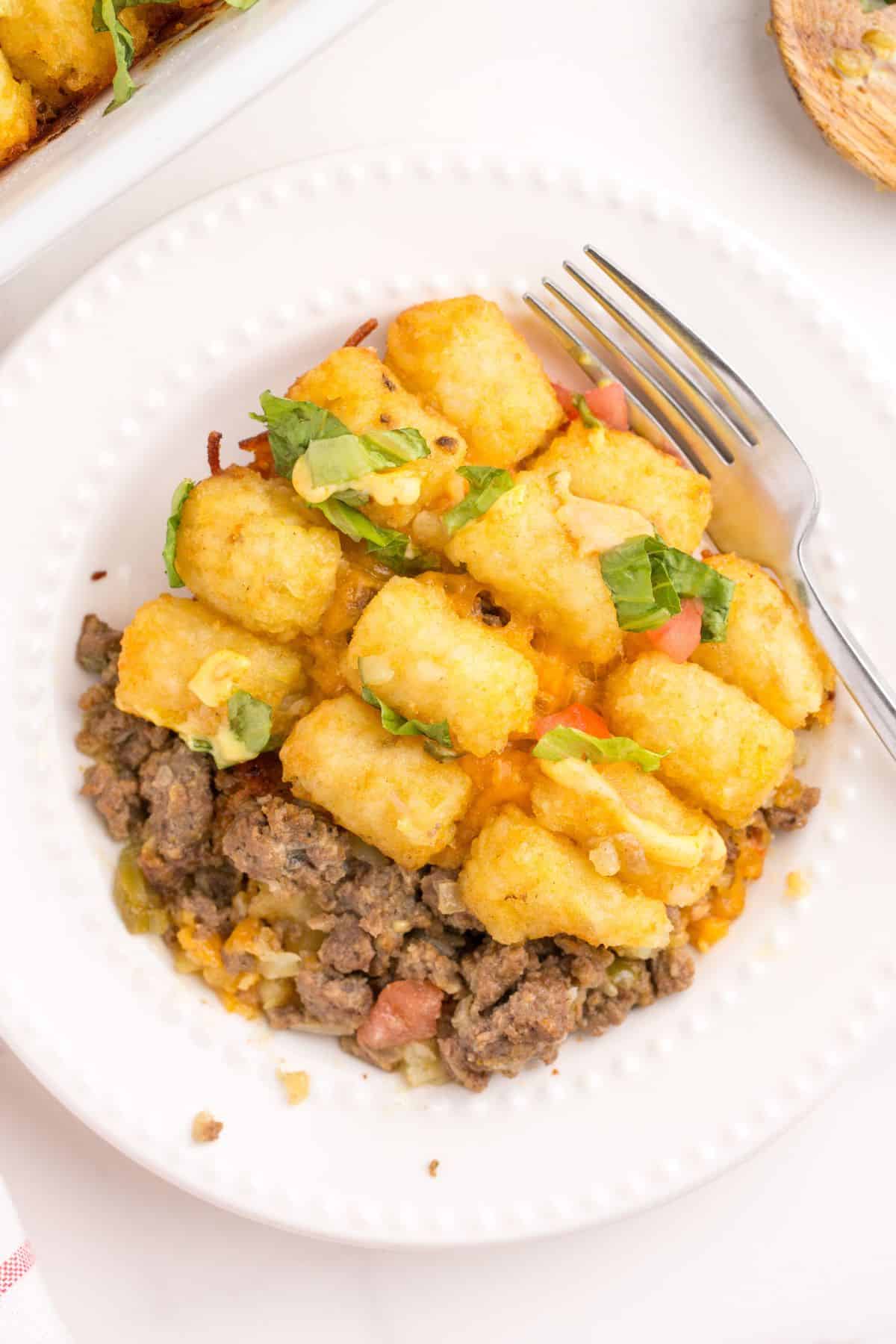A serving of big mac casserole on a white dinner plate.