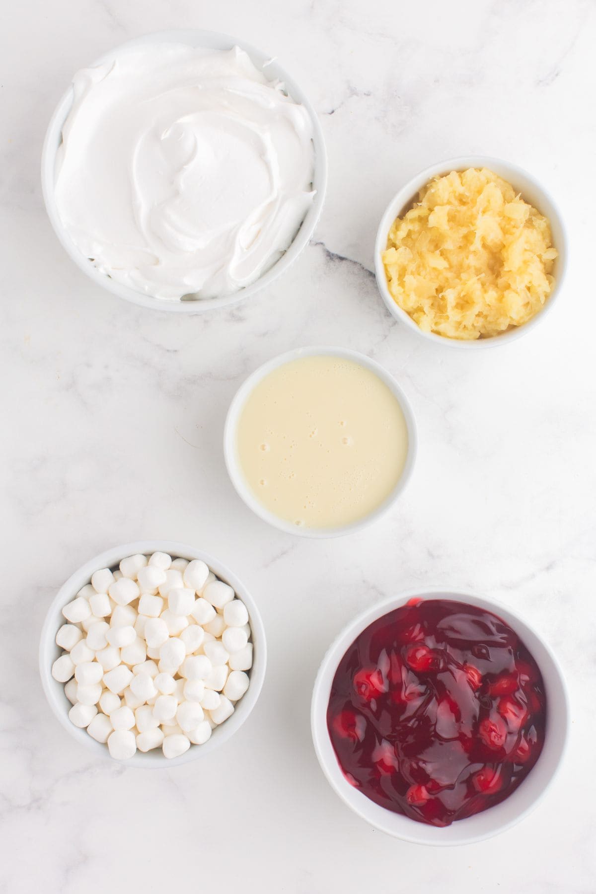 Ingredients for cherry fluff: Cool Whip, crushed pineapple, condensed milk, marshmallows, and cherry pie filling.