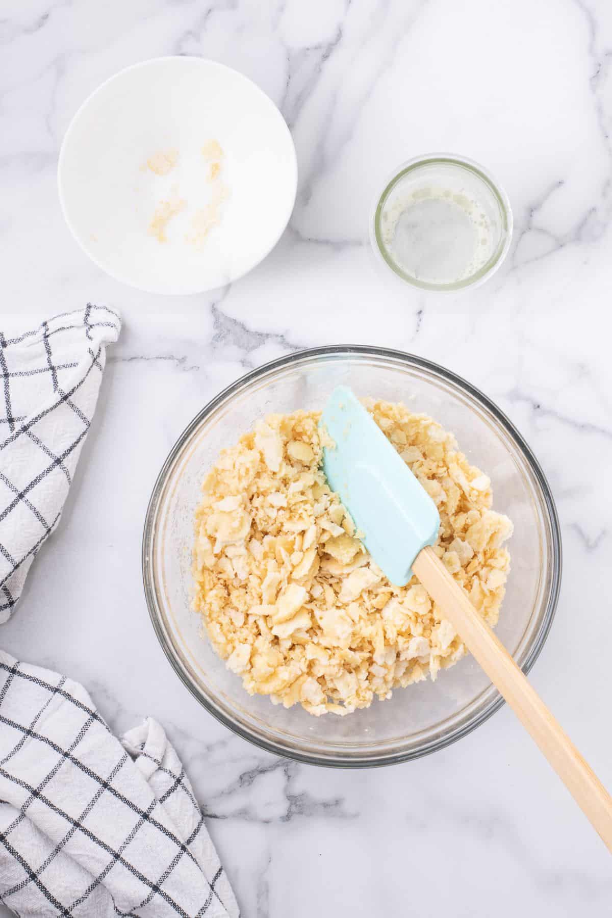 Ritz crackers crushed and mixed with melted butter in a glass mixing bowl.
