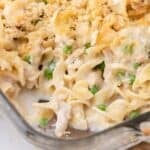 Tuna casserole in a glass baking dish. A serving has been removed from the corner of the baking pan.