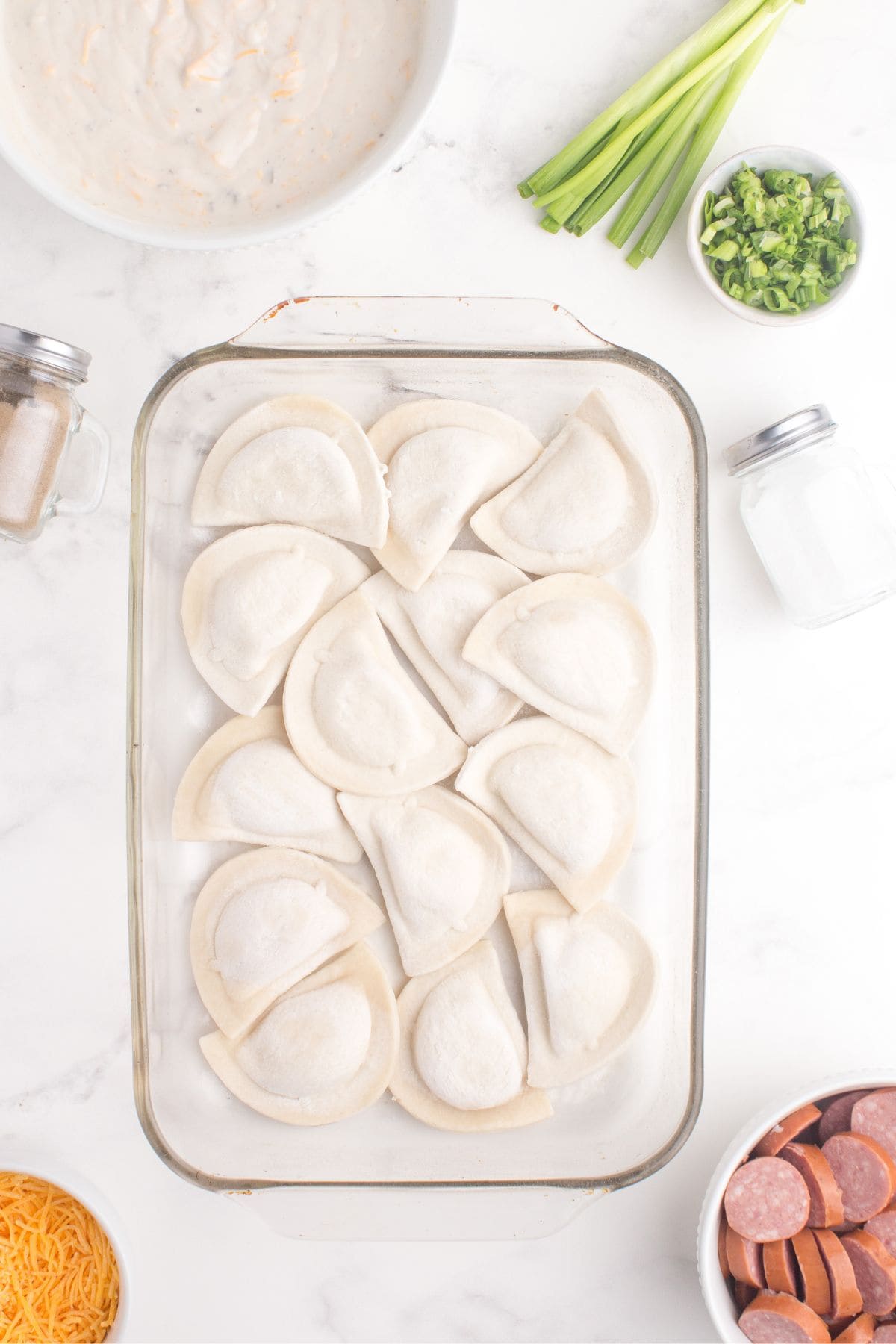A single layer of pierogi placed at the bottom of a glass baking pan.