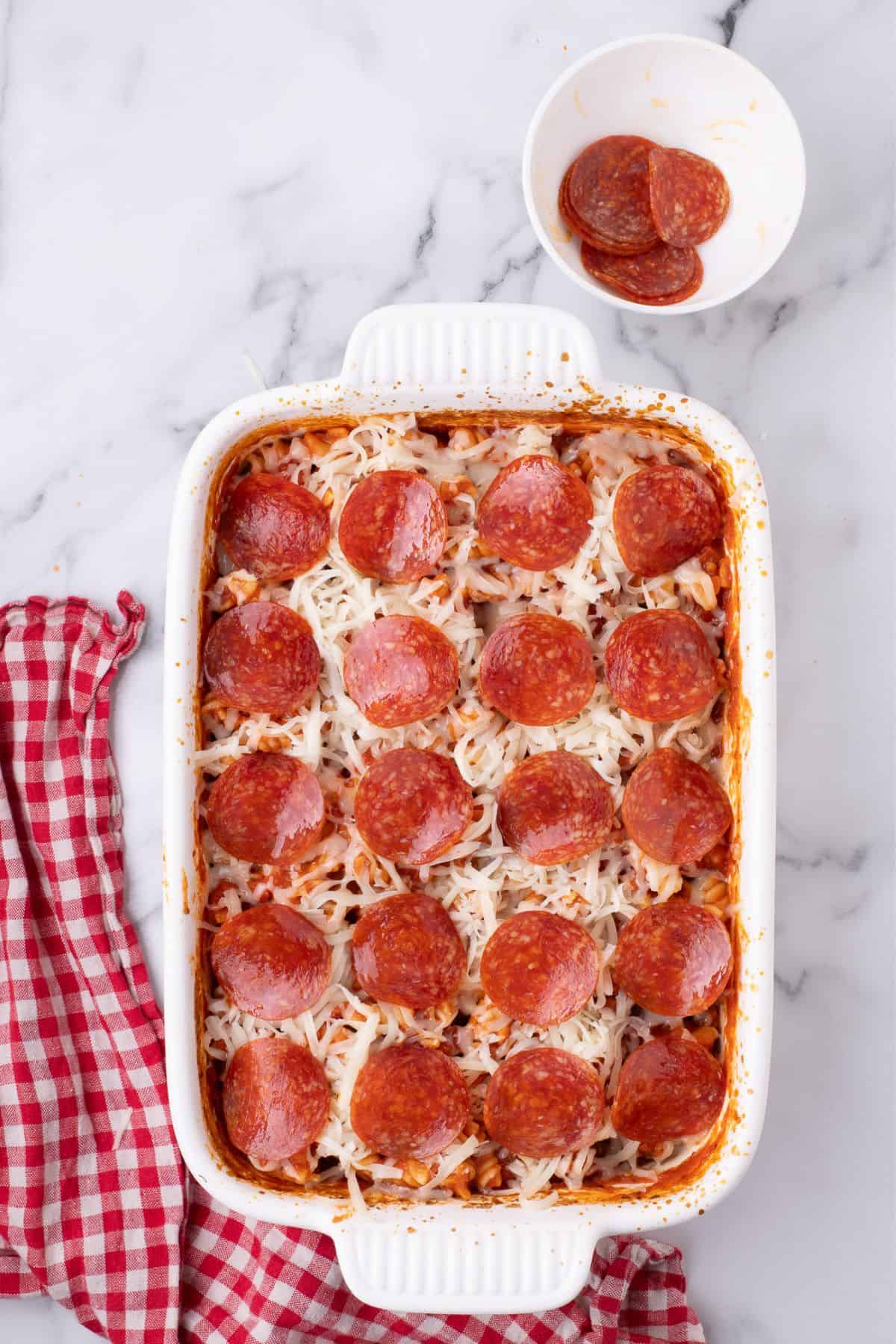Pepperoni added to the baking dish.