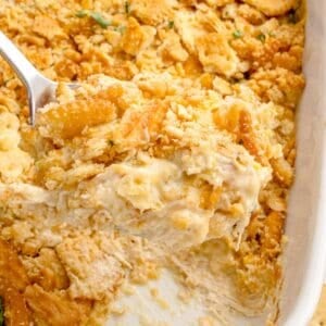 Chicken casserole in a white baking dish. A serving has been removed from the corner of the dish.