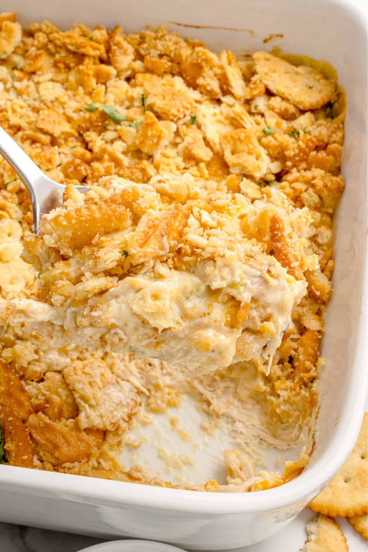 Chicken casserole in a white baking dish. A serving has been removed from the corner of the dish.