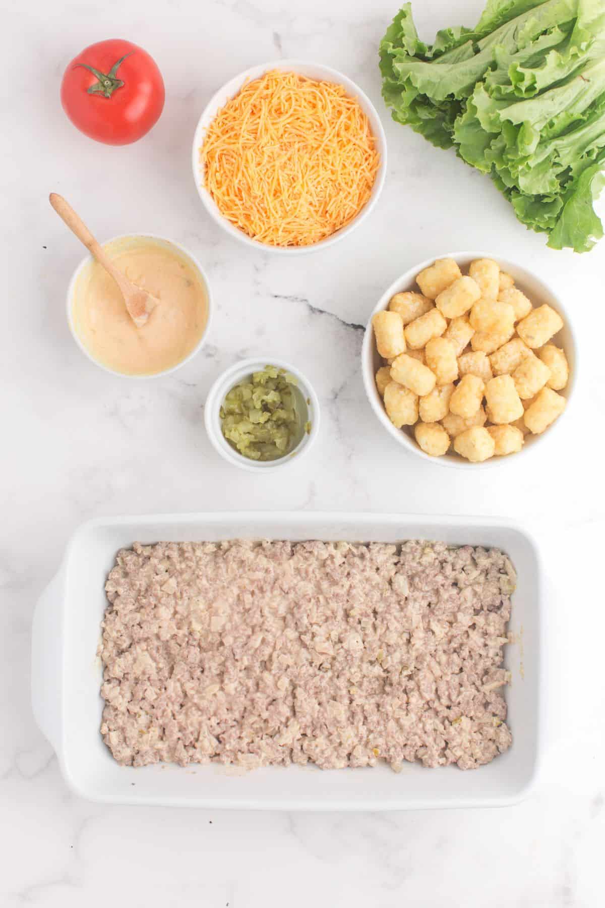 Big mac casserole burger ingredients in the casserole dish.