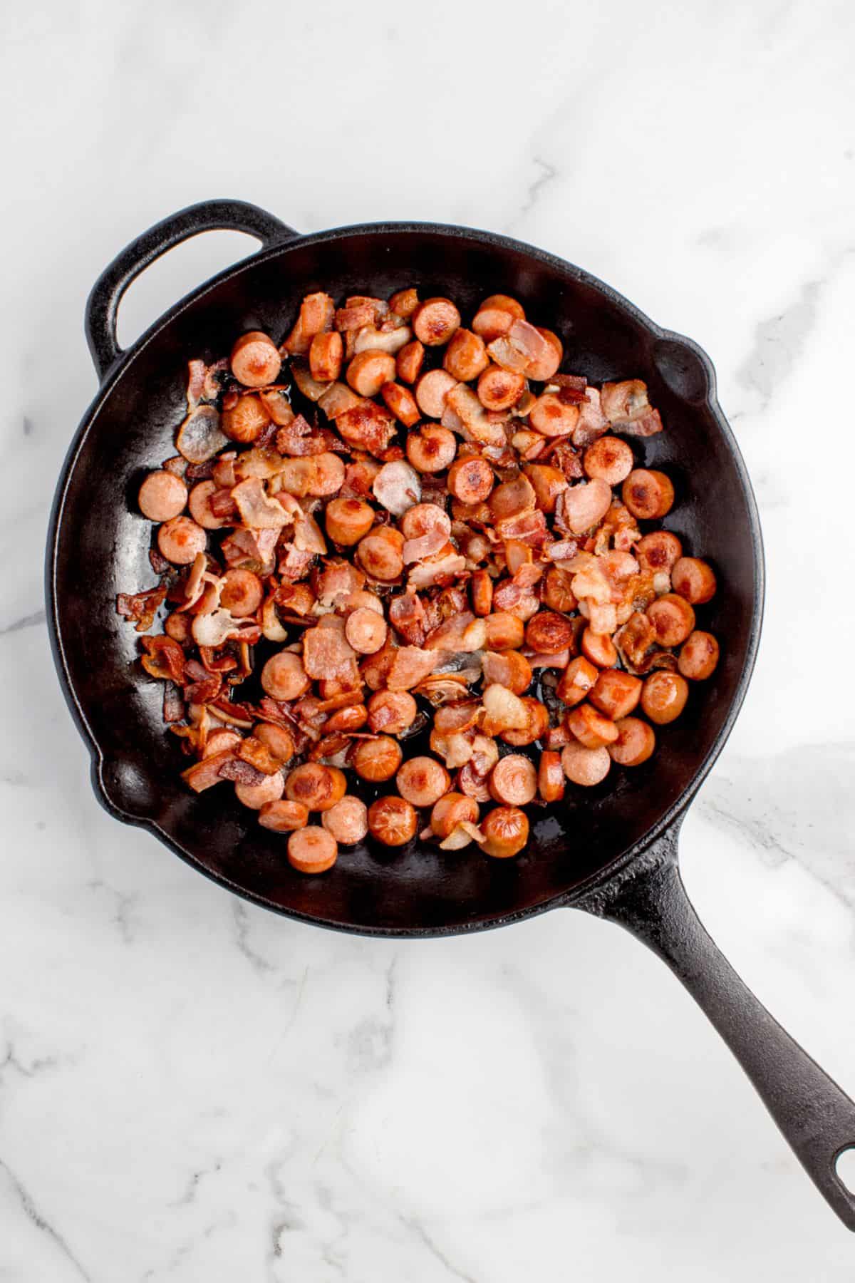 Chopped hot dogs and bacon are sauteed together until the bacon is cooked through.