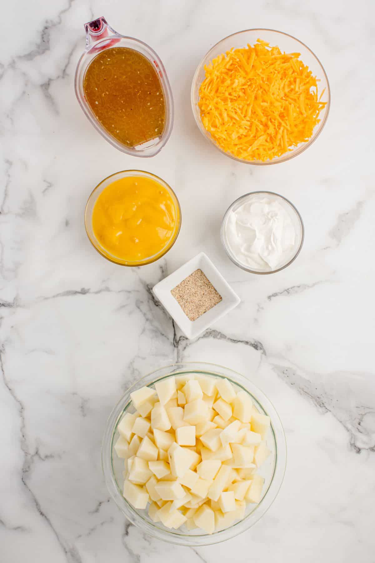 Ingredients for cheesy potato soup: potatoes, sour cream, shredded cheddar cheese, cream of chicken soup, chicken stock, and McCormick all purpose seasoning.