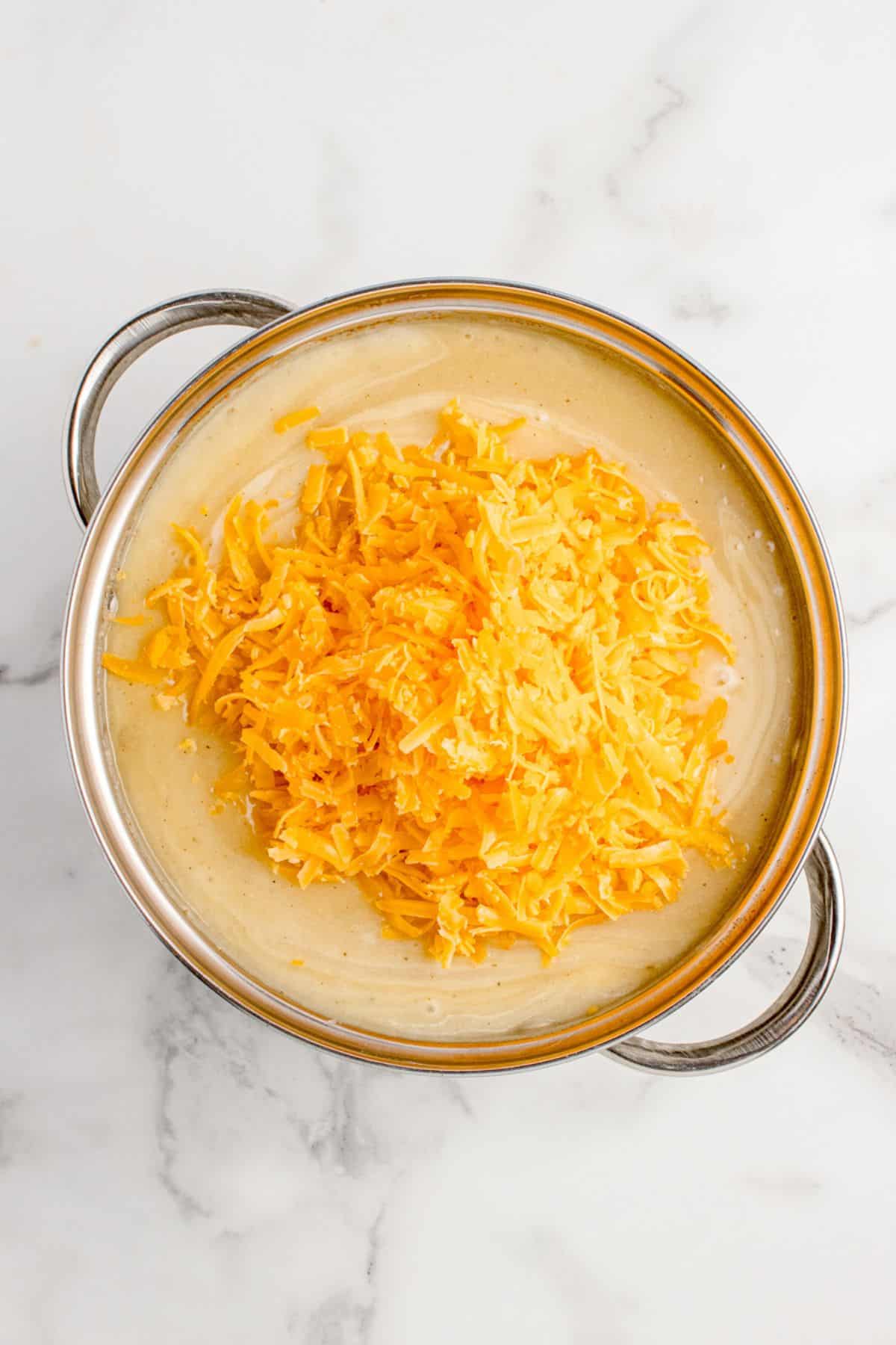 Shredded cheddar cheese is added to the soup.