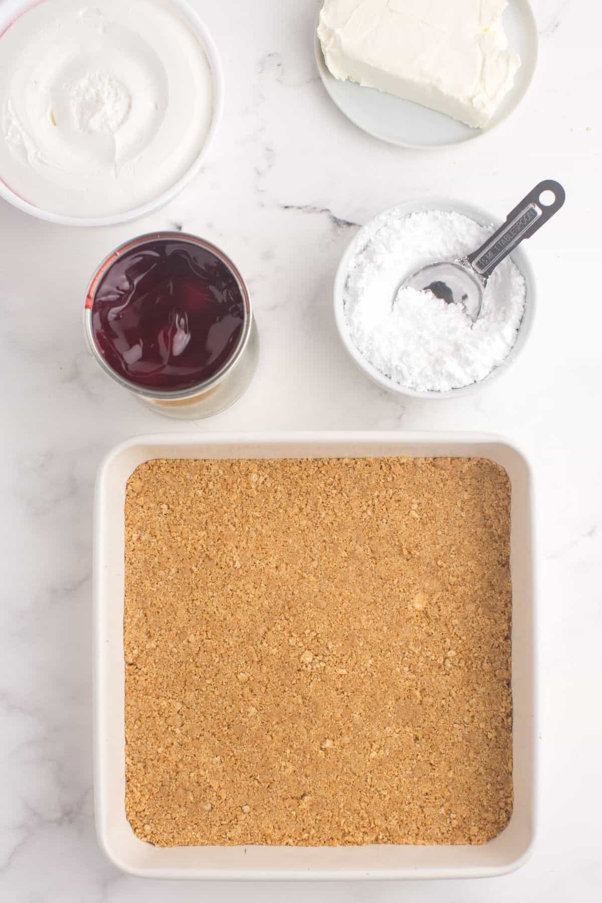 Graham cracker crust pressed into the bottom of a square baking pan.