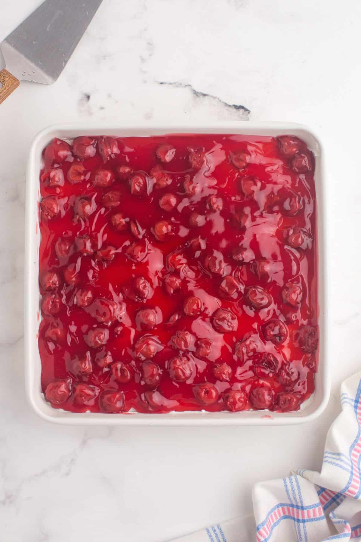 Cherry pie filling evenly spread on top of cream cheese layer.