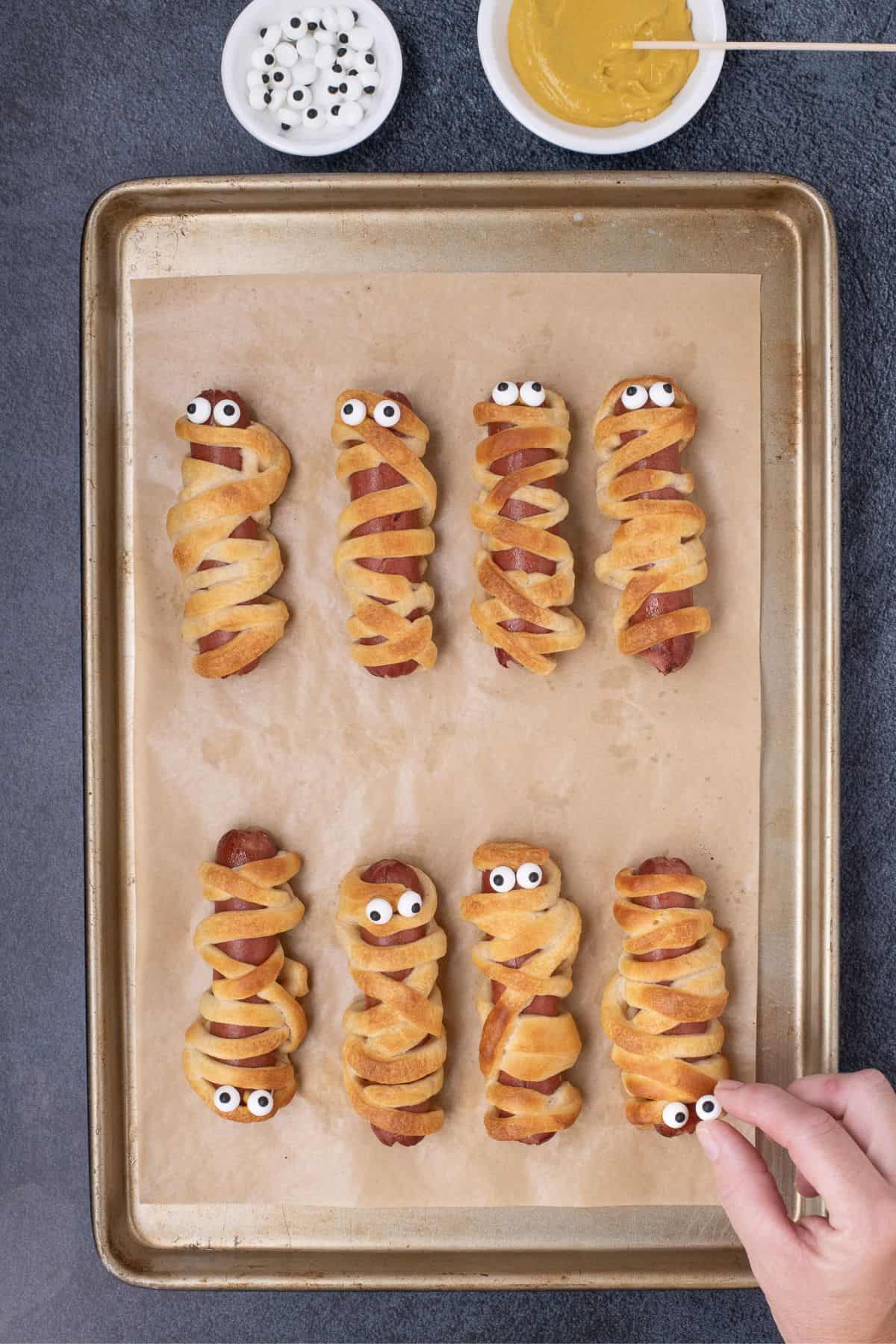 Candy eyeballs added to hot dog mummies.