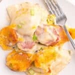 Close up of the pierogi casserole scooped out onto a white plate with a fork.