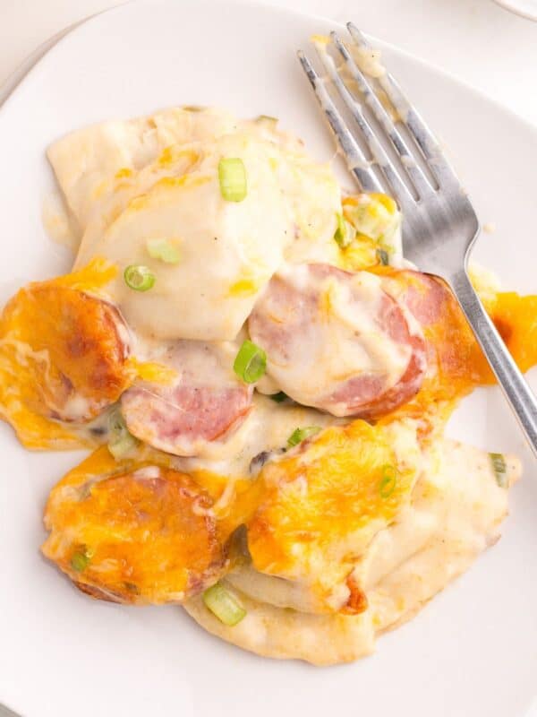 Close up of the pierogi casserole scooped out onto a white plate with a fork.