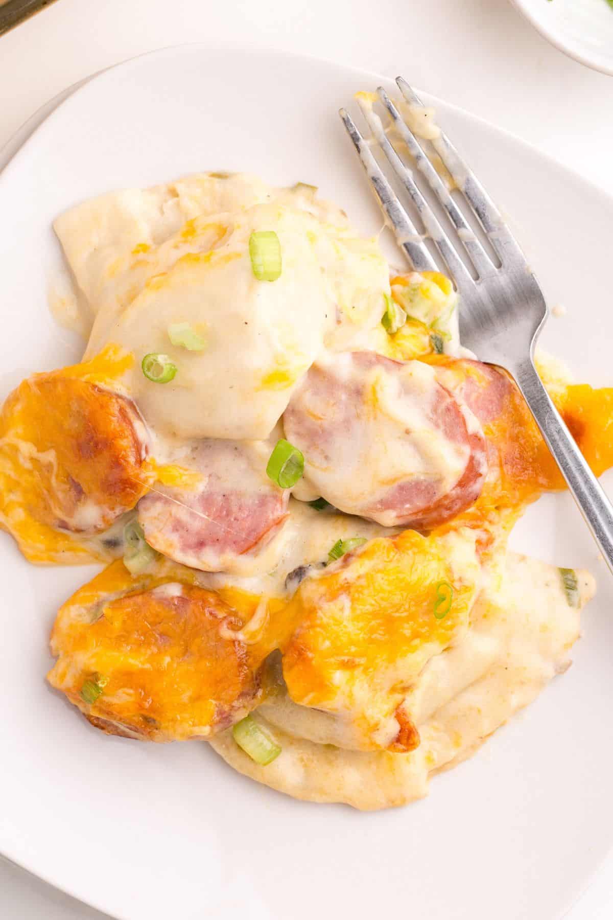 Close up of the pierogi casserole scooped out onto a white plate with a fork.